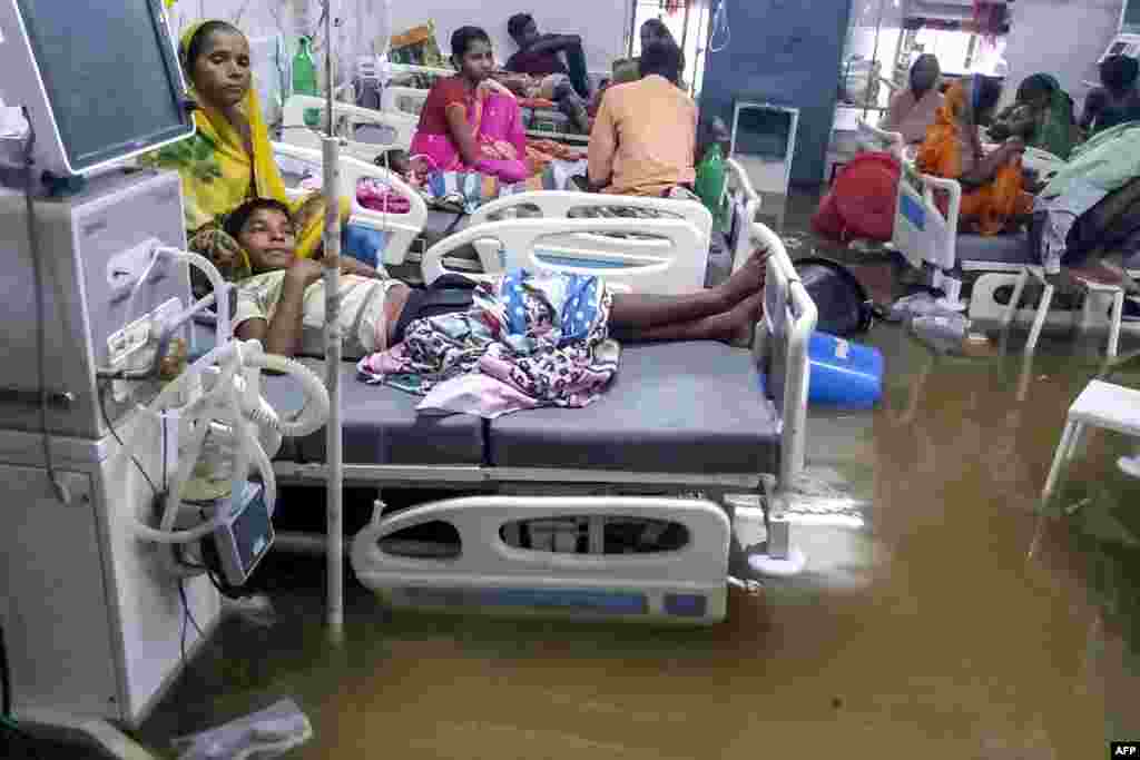 Patients and their relatives rest in beds as they wade through floodwaters during heavy monsoon rain at waterlogged Nalanda Medical College and Hospital in Patna in the northeastern state of Bihar, India, Sept. 28, 2019.