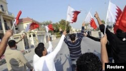Anti-government protesters holding Bahraini flags walk in front of riot police during a protest held by al-Wefaq in Manama, January 7, 2012.
