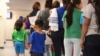 FILE - A photo provided by U.S. Immigration and Customs Enforcement shows mothers and their children standing in line at South Texas Family Residential Center in Dilley, Texas, Aug. 9, 2018.