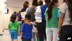 FILE - A photo provided by U.S. Immigration and Customs Enforcement shows mothers and their children standing in line at South Texas Family Residential Center in Dilley, Texas, Aug. 9, 2018.
