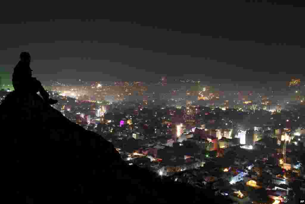 Seorang pria duduk di atas bukit, menikmati kembang api menghiasi langit di atas Ajmer, negara bagian Rajasthan, India (3/11). (AP/ Deepak Sharma)