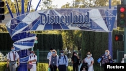 Para pengunjung menunggu di bawah papan nama Disneyland Resort di Disneyland Park pada hari dibukanya kembali Disney California Adventure di tengah pandemi COVID-19, di Anaheim, California, AS, 30 April 2021. (REUTERS/Mario Anzuoni)
