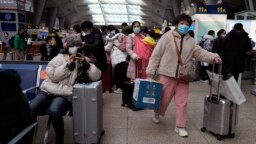 北京南站戴着口罩的旅客在候车室里等待。（2022年1月14日）