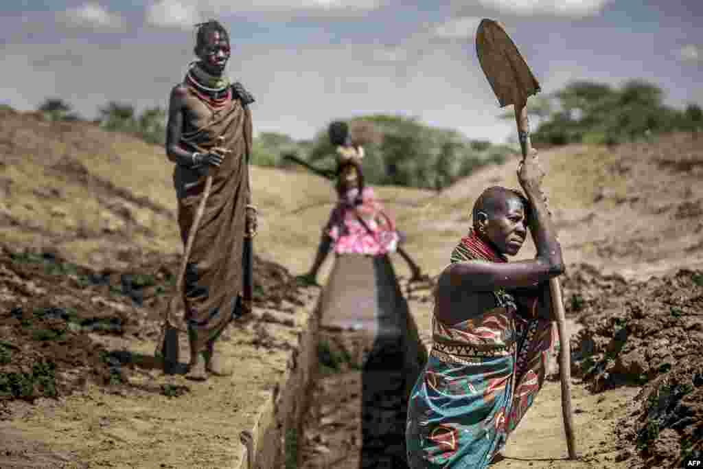 Members of the Turkana community work unblocking an irrigation canal to provide water to their sorghum crops in an arid dry area in Nanyee, near Lodwar, Turkana County, Kenya.