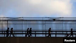 La gente cruza un puente peatonal en el puerto de entrada de San Ysidro en San Ysidro, California, foto de archivo.