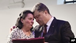 Ukrainian President Petro Poroshenko, right, presents a Hero of Ukraine award to a relative of an activist killed a year ago during mass protests, at the award ceremony in Kyiv, Feb. 20, 2015.