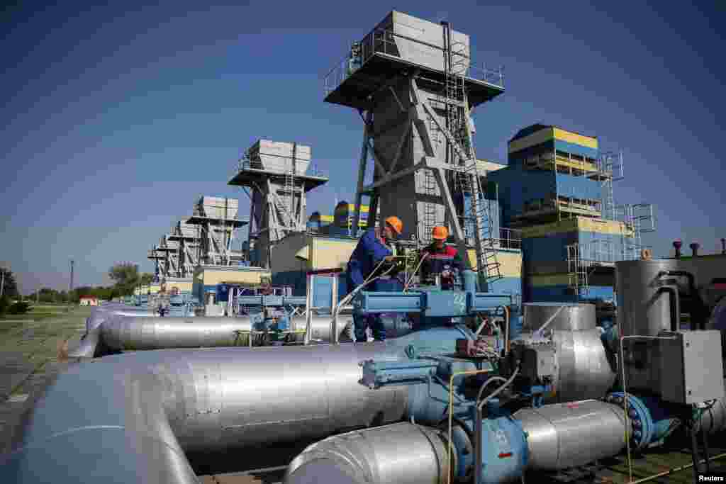 Workers stand near pipes at a gas compressor station near Uzhhorod May 21, 2014. Russia has said state-controlled exporter Gazprom will not supply transit nation Ukraine with gas for its own use in June if Kiev fails to pay in advance and has warned a cut