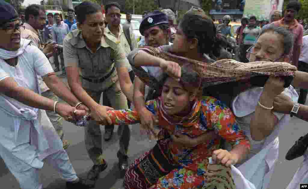 Cảnh sát Ấn Độ bắt giữ những nhà hoạt động của tổ chức Trung tâm Đoàn kết Xã hội của Ấn Độ khi họ chặn một con đường trong một cuộc biểu tình phản đối một vụ cưỡng hiếp tập thể ở thành phố Kolkata, Ấn Độ.