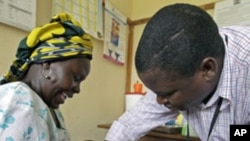 Iren Salama (L) holds her baby Pendo as it is given an injection as part of a malaria vaccine trial at a clinic in the Kenya coastal town of Kilifi, November 23, 2010