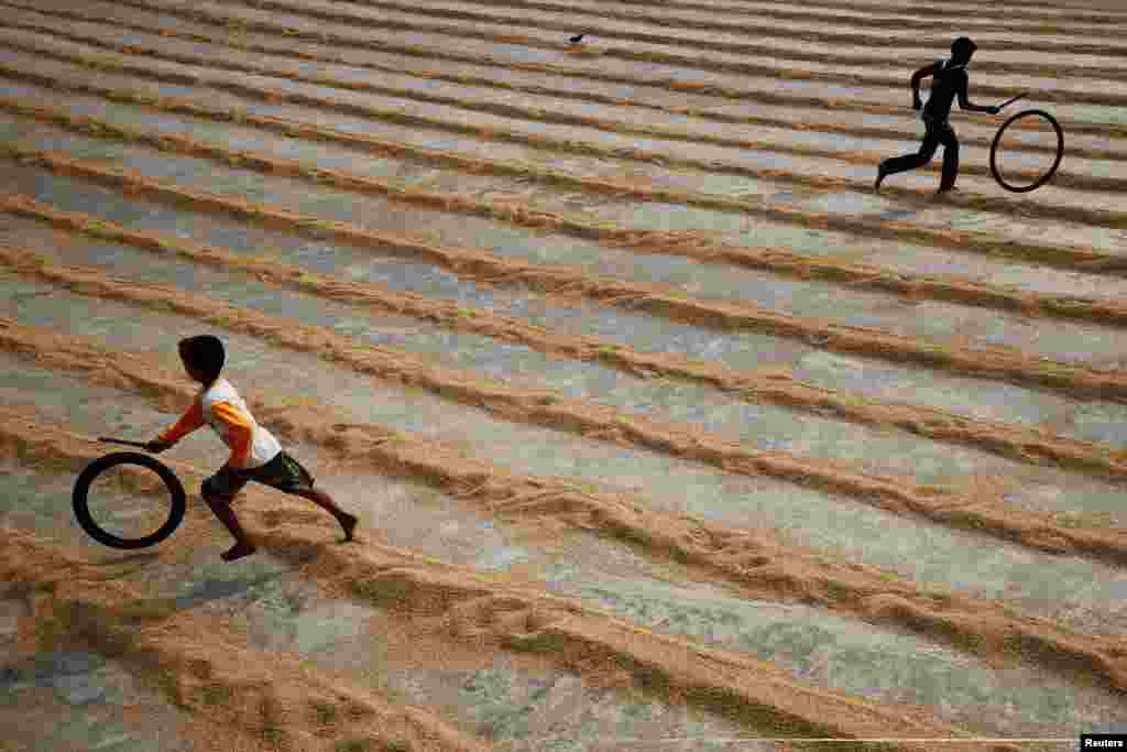 Children play with bicycle tires at a rice-processing mill in Muktarpur, on the outskirt of Dhaka, Bangladesh.