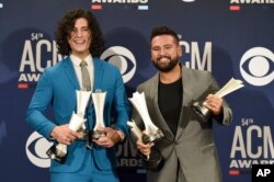 Dan Smyers, (izquierda) y Shay Mooney, del dúo Dan + Shay, posan para la prensa con los premios por canción del año y sencillo del año por "Tequila," y de dúo del año en la 54 entrega anual de los premios ACM en Las Vegas, Nevada, el domingo, 7 de abril de 2019.