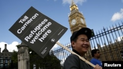A protester holds up a placard during a demonstration in London to express solidarity with migrants and to demand the government welcome refugees into Britain, Sept. 12, 2015.