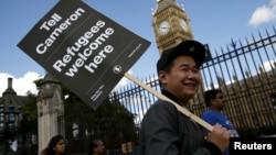 A protester holds up a placard during a demonstration in London to express solidarity with migrants and to demand the government welcome refugees into Britain, Sept. 12, 2015.