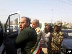 In this photo provided by the Iranian Students' News Agency, ISNA, Revolutionary Guard members carry a wounded comrade after a shooting during their parade marking the 38th anniversary of Iraq's 1980 invasion of Iran, in the southwestern city of Ahvaz, Iran, Sept. 22, 2018.