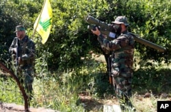 A Hezbollah fighter holds an Iranian-made anti-aircraft missile, right, as he takes his position with his comrade between orange trees, at the coastal border town of Naqoura, south Lebanon, April 20, 2017.
