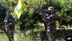FILE - A Hezbollah fighter holds an Iranian-made anti-aircraft missile, right, as he takes his position with his comrade between orange trees, at the coastal border town of Naqoura, south Lebanon.