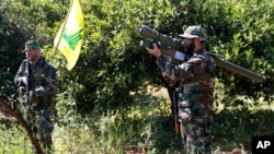 FILE - A Hezbollah fighter holds an Iranian-made anti-aircraft missile, right, as he takes his position with his comrade between orange trees, at the coastal border town of Naqoura, south Lebanon, April 20, 2017.