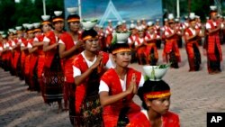 FILE - Indonesian girls put bowls of holy water on their heads as they perform a traditional dance during the opening ceremony of Lake Toba Festival on Samosir island, North Sumatra, Indonesia.