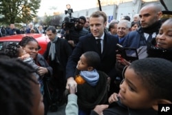 French President Emmanuel Macron, center, meets residents of the Cite du Chene Pointu during his visit focused on the theme of urban planing in Clichy-sous-Bois, Nov. 13, 2017.