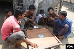 Displaced Rohingya men and boys play a Carrom board game in Baw Du Pha Camp 1 outside Sittwe. (P. Vrieze for VOA)