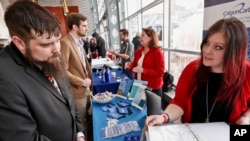 FILE - visitors to the Pittsburgh veterans job fair meet with recruiters at Heinz Field in Pittsburgh. 