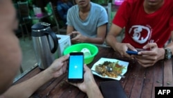 မိုဘိုင်းဖုန်းအသုံးပြုနေသူတဦးကို ရန်ကုန်မြို့ရှိ လက်ဖက်ရည်ဆိုင်တခုမှာ တွေ့ရ။ (ဒီဇင်ဘာ ၁၈၊ ၂၀၁၈)