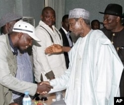 President Yar'Adua (C), flanked by then-Vice President Goodluck Jonathan (R), shakes hands with Government Ekpemupolo (L), commander of rebel group MEND, during their meeting in Abuja on 09 October 2009.