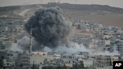 Asap tebal dan puing-puing mengepul akibat serangan udara koalisi yang dipimpin AS di Kobani, Suriah (18/10).