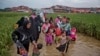 缅甸的罗兴亚穆斯林趟过积水的道路走向设在孟加拉国境内的难民营。（2017年11月17日）