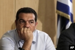 ​ນາຍົກລັດຖະມົນຕີ ກຣິສ ທ່ານ Alexis Tsipras ກຳລັງຮັບຟັງ ໃນລະຫວ່າງ ການເດີນທາງໄປຢ້ຽມຢາມ ກະຊວງຄົມມະນາຄົມ ຂົນສົ່ງ ໃນນະຄອນຫຼວງ Athens, ວັນທີ 12 ສິງຫາ 2015.