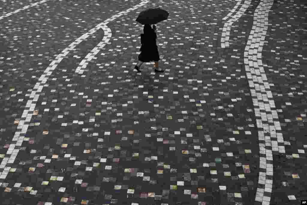 A woman walks with an umbrella during a summer rainfall at Monastiraki square in central Athens, Greece.