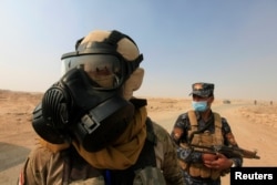 Iraqi forces wear protective masks after winds brought fumes from a nearby sulfur plant set alight by Islamic State militants, south of Mosul in Qayyara, Iraq, Oct. 22, 2016.