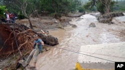 Seorang pria menyebrangi sungai dengan tali setelah jembatan ambruk karena badai Manuel di kota Petaquillas, Meksiko (18/9). (Foto: Dok)