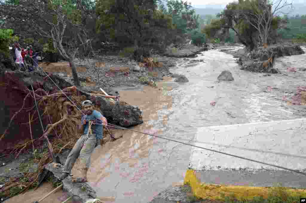 A man uses a makeshift zip line to cross a river after a bridge collapsed under the force of the rains caused by Tropical Storm Manuel near the town of Petaquillas, Mexico, Sept. 18, 2013.