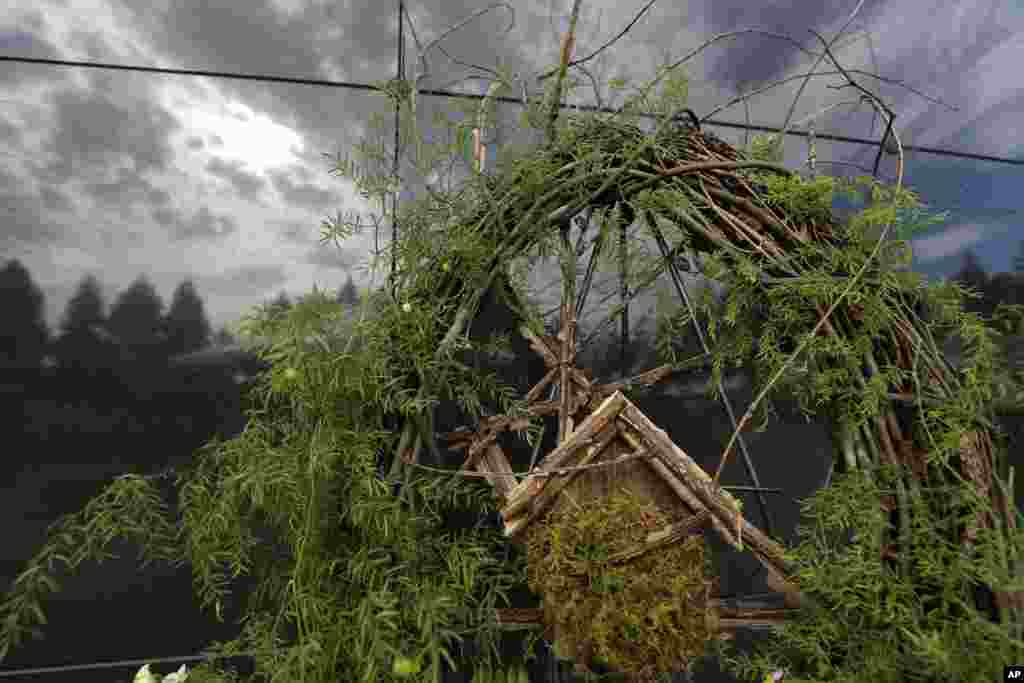 A rendering of a house is seen on a wreath during a wreath-laying ceremony at the Hurricane Katrina Memorial in New Orleans, Louisiana. The sky is reflected on an unmarked mausoleum that contains unidentified bodies of people who died in the storm nine years ago. &nbsp;