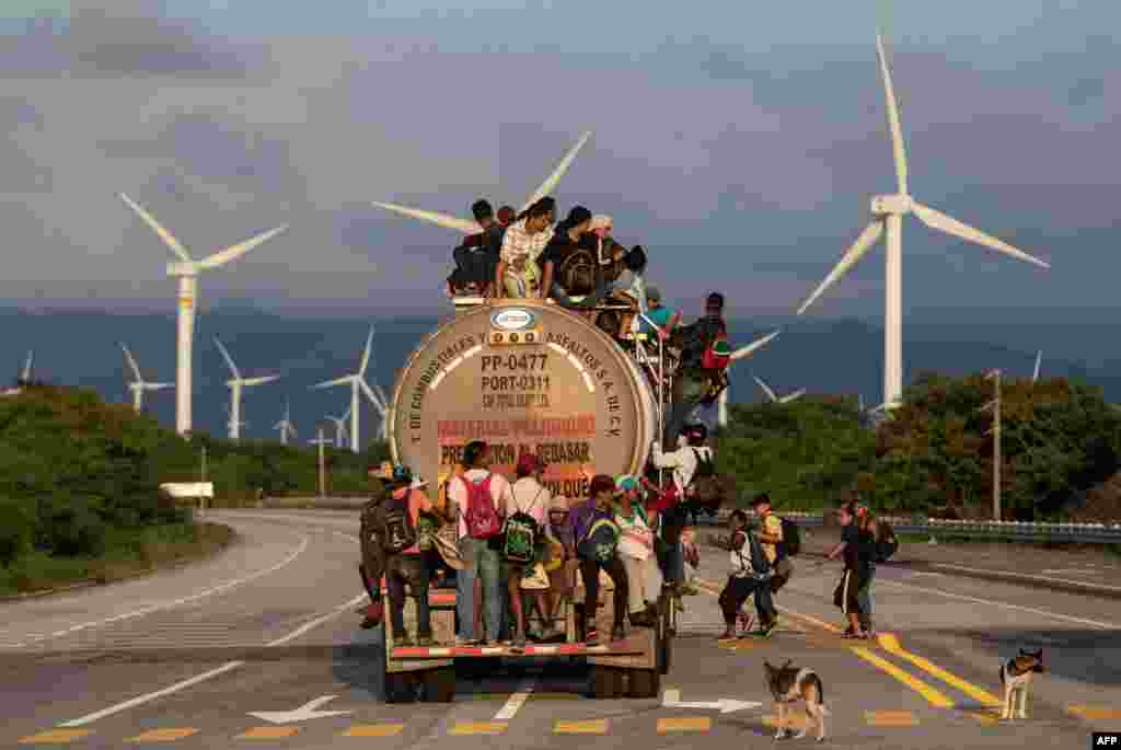 A truck carrying mostly Honduran migrants taking part in a caravan heading to the U.S., passes by a wind farm on their way from Santiago Niltepec to Juchitan, near the town of La Blanca in Oaxaca State, Mexico.