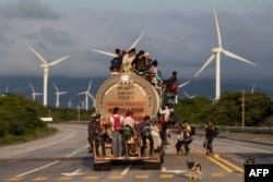 A truck carrying mostly Honduran migrants taking part in a caravan heading to the U.S., passes by a wind farm on their way from Santiago Niltepec to Juchitan, near the town of La Blanca in Oaxaca State, Mexico, Oct. 30, 2018.