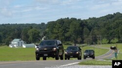 Official vehicles drive down a road near Camp David, Md., Aug. 18, 2017.