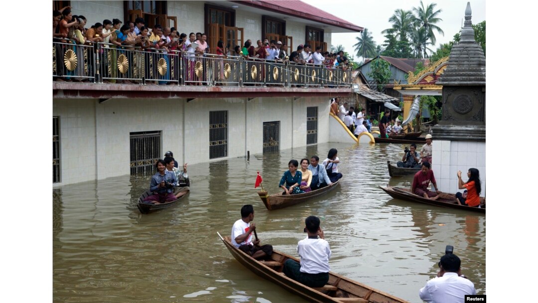 FILE - Myanmar opposition leader Aung San Suu Kyi, center, rides a boat as she leaves after visiting a monastery where flood victims are sheltered in Bago, 80 kilometers (50 miles) northeast of Yangon, Myanmar, Monday, Aug. 3, 2015.