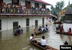FILE - Myanmar opposition leader Aung San Suu Kyi, center, rides a boat as she leaves after visiting a monastery where flood victims are sheltered in Bago, 80 kilometers (50 miles) northeast of Yangon, Myanmar, Monday, Aug. 3, 2015.