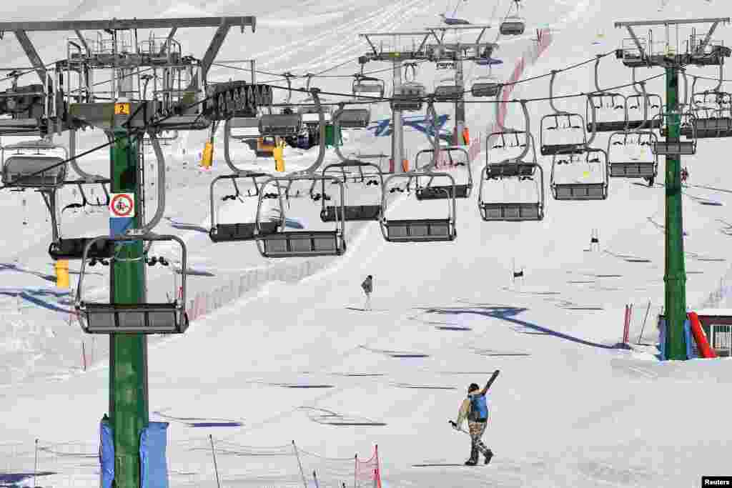 A person carrying skies climbs up the hill after government signed a last minute order to keep ski resorts closed until March, due to the COVID-19 pandemic, in Ponte di Legno, Italy.