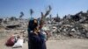 A Palestinian woman holds her daughter as they walk past the ruins of destroyed houses in Khuzaa town, which witnesses say was heavily hit by Israeli shelling and air strikes during the Israeli offensive, in the east of Khan Younis, in the southern Gaza Strip, Aug. 7, 2014.