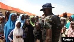 Un personnel de la sécurité fait signe aux réfugiés du camp de Bakkasi pour les déplacés internes après une manifestation contre les rations de nourriture trop petites, à Maiduguri, dans l'État de Borno, Nigeria, le 29 août 2016. 
