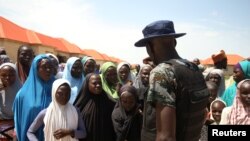 Un soldat fait signe aux déplacés du camp de Bakkasi après une manifestation contre les rations de nourriture insufficantes, à Maiduguri, dans l'État de Borno, Nigeria, le 29 août 2016. 