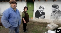 Ivanka and Krustyo Tonev pose next to the mural depicting German chancellor Angela Merkel, in the Bulgarian village of Staro Zhelezare, Jan. 27, 2016.