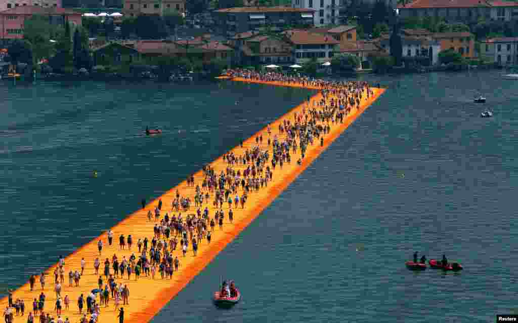 People walk on the installation &#39;The Floating Piers&#39; by Bulgarian-born artist Christo Vladimirov Yavachev, known as Christo, on Lake Iseo, northern Italy.