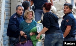 A woman, second left, cries after she was rescued from her home following a quake in Amatrice, central Italy, Aug. 24, 2016.
