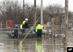 In this photo provided by the Missouri State Highway Patrol, Water Patrol troopers assist utility company employees in shutting off natural gas lines in floodwaters at Craig, Mo., March 20, 2019.