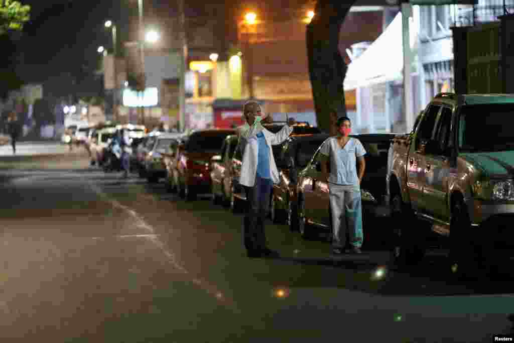 Los doctores Carlos Martínez y María Martínez esperan en la fila para obtener combustible en una estación de servicio de Caracas durante la cuarentena nacional debido al brote de la enfermedad por coronavirus.