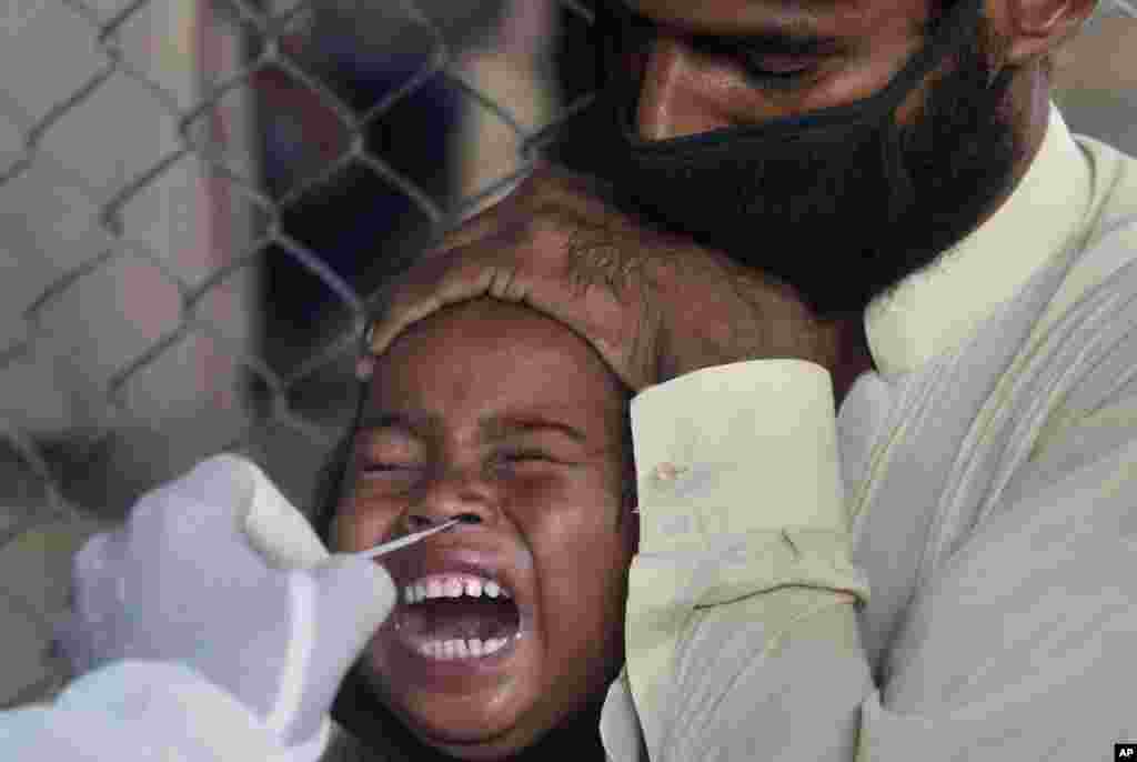 A girl reacts while getting a nasal swab sample at a testing and screening facility for the new coronavirus in a hospital in Karachi, Pakistan, Friday, July 17, 2020. (AP Photo/Fareed Khan)